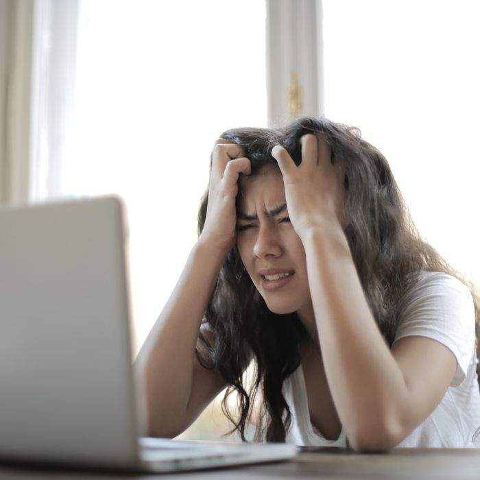 Frustrated student with hands in her hair in front of a laptop